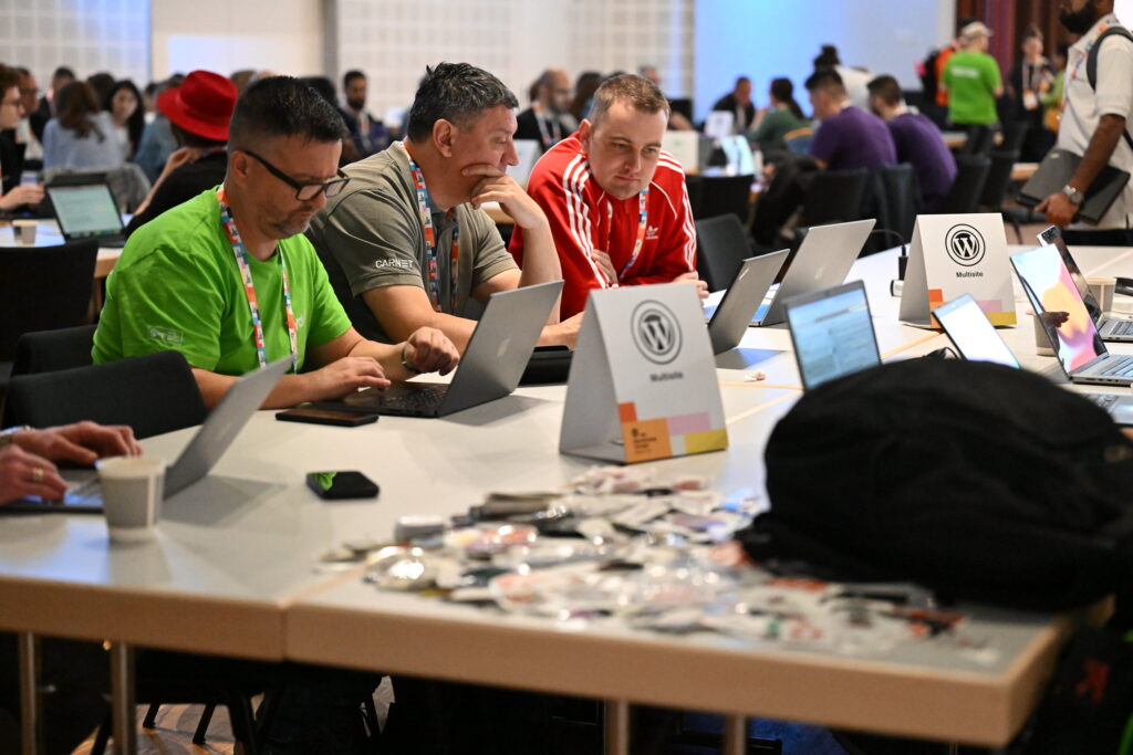 a group of men sitting at a table with laptops